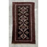 A Persian rug with repeating geometric motifs on a black ground within a multi border, 113 by