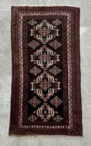 A Persian rug with repeating geometric motifs on a black ground within a multi border, 113 by