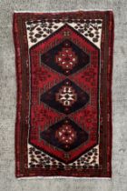 A Persian Hamadan woollen hand knotted rug with three central guls within borders, 152 by 90cms.