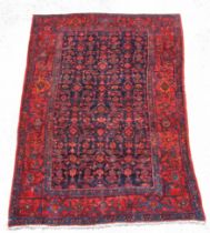 A Persian hand knotted woollen rug with all over design, on a red ground, 183 by120cms (74).