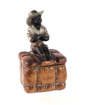 A 19th century French terracotta tobacco box and cover in the form of a seated black boy on a bale