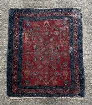 A Caucasian rug, having repeating floral motifs on a red ground and a multi border, 110cm by 94cm.