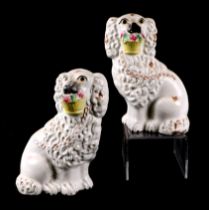 A pair of 19th century Staffordshire figures depicting dogs holding baskets of flowers in their