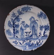 An early 18th century English Delft shallow dish decorated with a chinoiserie scene depicting a lady