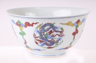 A Chinese Wucai style footed bowl decorated with dragons amongst clouds, six character blue mark