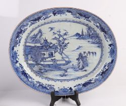 A large 18th century Chinese blue & white oval meat plate decorated with a river landscape scene,