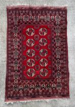 A Persian rug with repeated medallion design, on a red ground, 133 by 207cms.