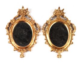 A pair of rococo style carved giltwood miniature wall mirrors, each 22cms high (2).