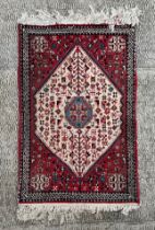 A Persian prayer rug, having a central floral medallion on a red ground, 98cm by 66cm.