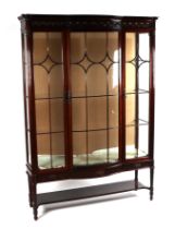 An Edwardian carved mahogany bowfronted display cabinet with three astragal glazed panelled doors