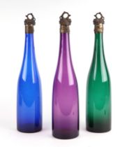 Three late 19th Century coloured glass wine bottles with metal mounts and stoppers, decorated grapes