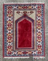 A Persian prayer rug, having a central motif on a maroon ground within a multi geometric border,