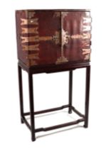 A Chinese leather covered trunk with copper reinforced strap work, the twin doors opening to