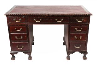 An early 20th century pedestal desk with an arrangement of nine drawers standing on ball and claw