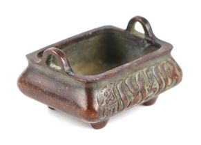 A Chinese bronze censer of small proportion with cast decoration, four squat feet and character mark