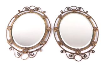 A pair of Regency style gilt brass oval wall mirrors, the frames with flowers to the rim and
