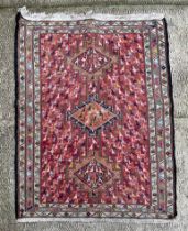 A Persian rug decorated with a multitude of stylised birds and animals, on a red ground, 102 by