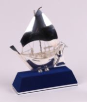 A silver model of a boat on a stand, boxed. boat 13cm long
