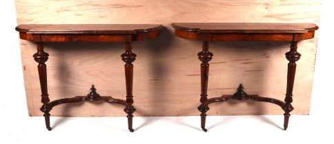 A pair of burr walnut console tables, the crossbanded shaped top above turned supports joined by a