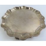 A silver salver, with pie crust edge and on three