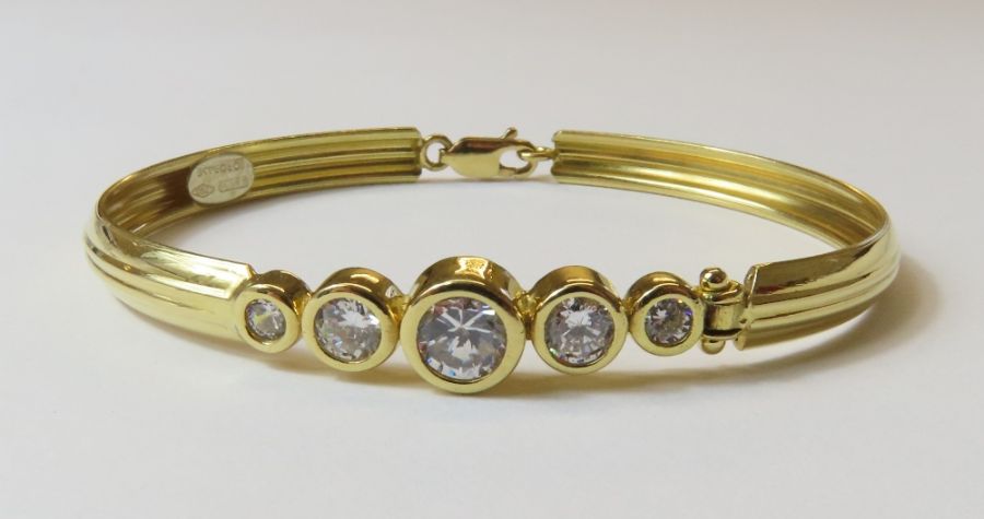 An oval bangle set with five graduated cubic zirco