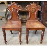 A pair of Victorian mahogany hall chairs, each wit