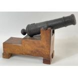 An iron cannon on a fitted oak stand, 35cm long