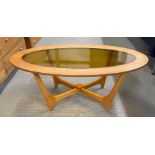 A mid century oval coffee table with inset amber g