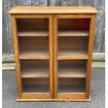 An early 20th century light oak bookcase fitted wi