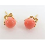 A pair of coral ear studs, the butterfly backs sta