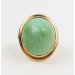 A ring set with a high domed light green hard stone ring, the band marked '14k', finger size J 1/2,