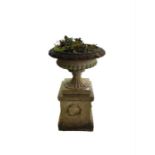 A garden urn in typical style on associated plinth
