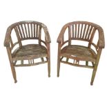 A pair of weathered teak garden armchairs by solid