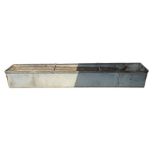 A long galvanised and rivetted drinking trough wit