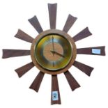 A mid century teak sunburst wall clock with brass