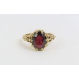 A 9ct gold garnet single stone ring, with decorati