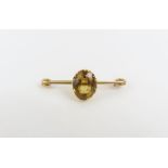 A bar brooch set with a single yellow paste stone,