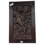 A carved oak panel worked with a wyvern holding a