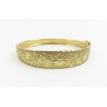 A 9ct gold bangle with diamond cut decoration, int