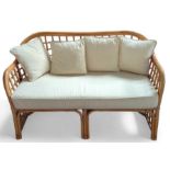 A bamboo framed two-seater sofa, with cream uphols