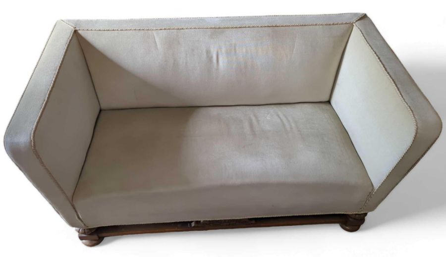 An oak framed two-seater sofa, raised on bun feet,