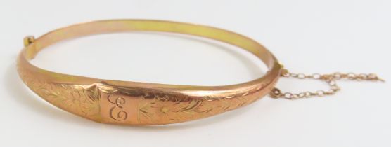 A 9ct gold hinged bangle, half engraved decoration