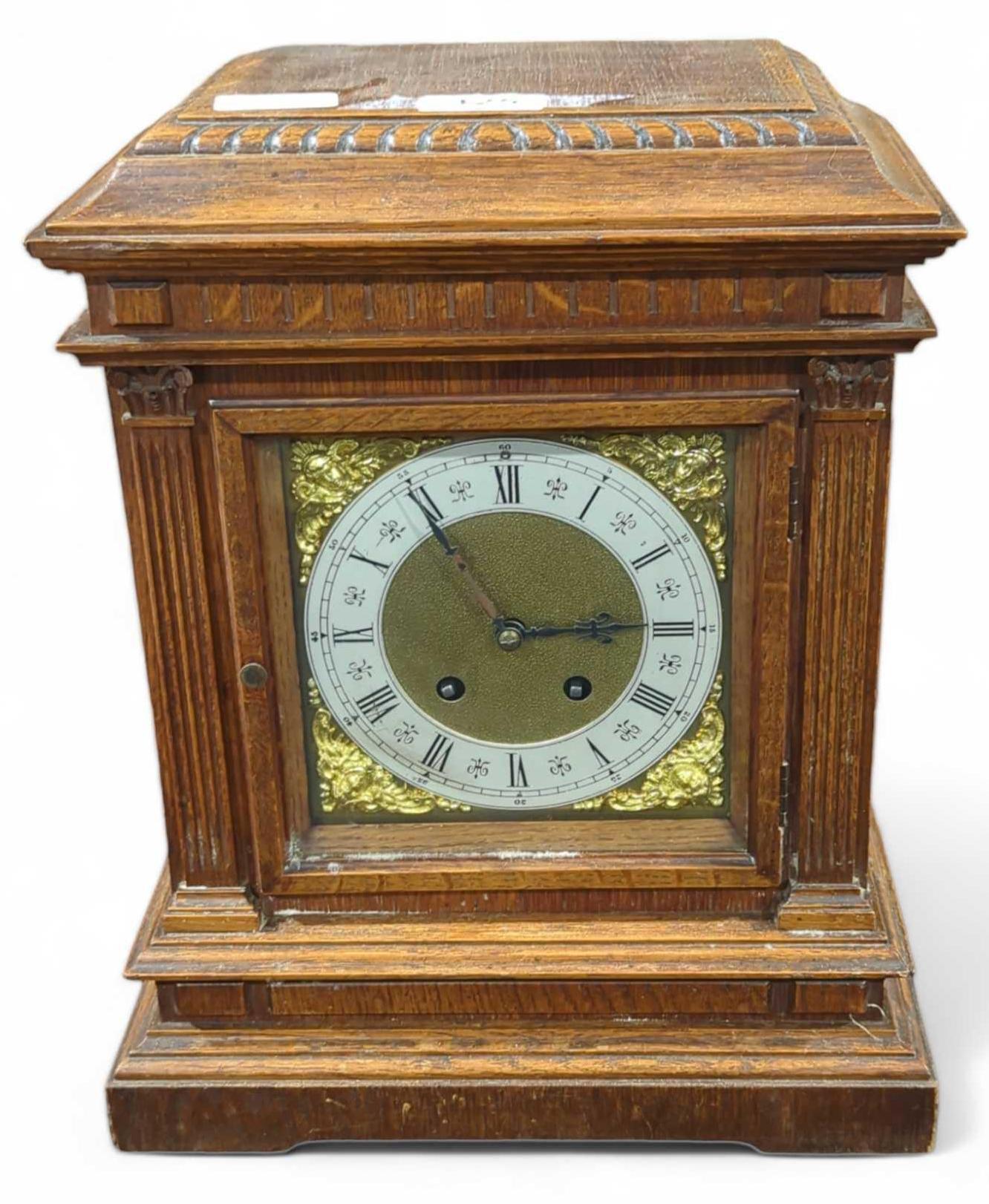 An Edwardian oak cased mantel clock striking on a