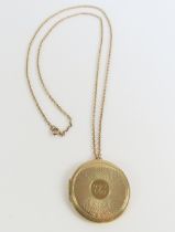 A round 9ct gold locket, the front with engine tur