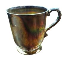 A silver mug, with scroll capped handle, on footed