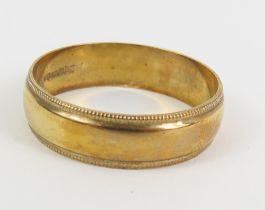 A 9ct gold wedding band, with a beaded edge to eac