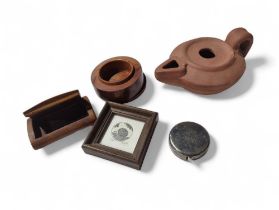 A small metal cased tape measure, a clay oil lamp,