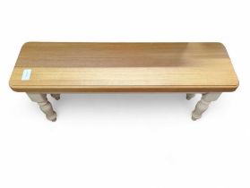 A modern light oak top bench, on white base, with