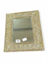A decorative wall mirror with wide embossed brass