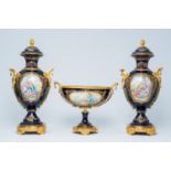 A French gilt mounted blue ground gold layered three-piece garniture with lovely scenes by Lebret, S